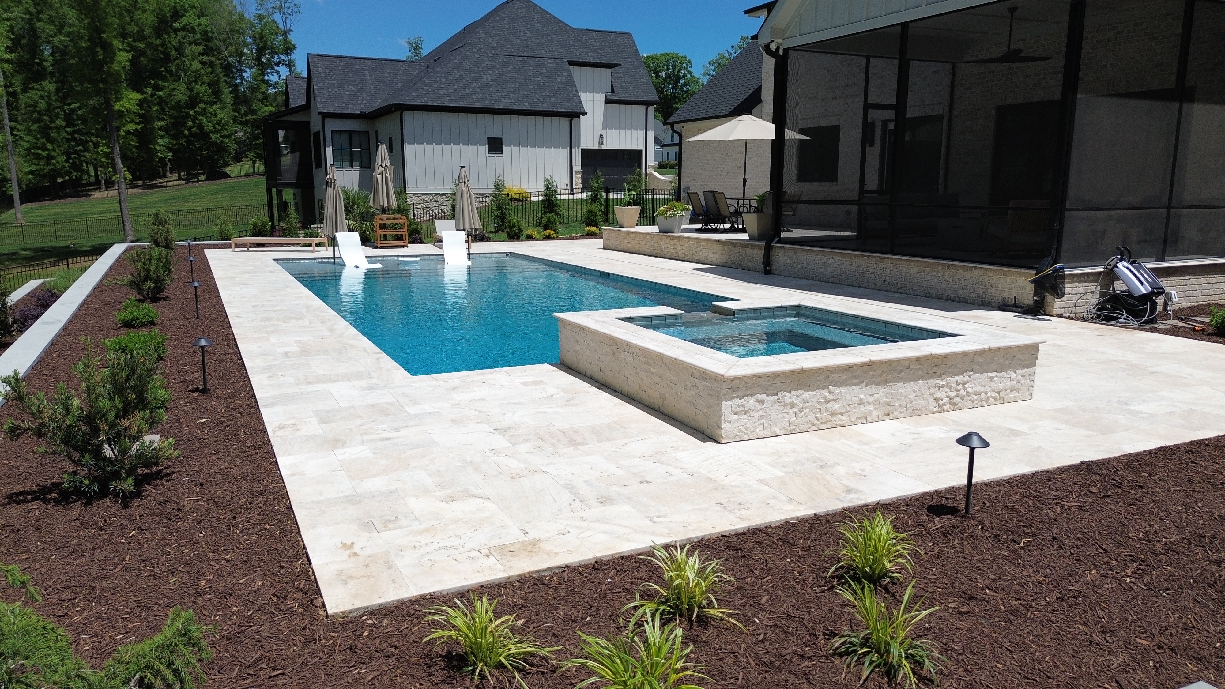 Rectangular concrete pool with travertine surround and raised spa